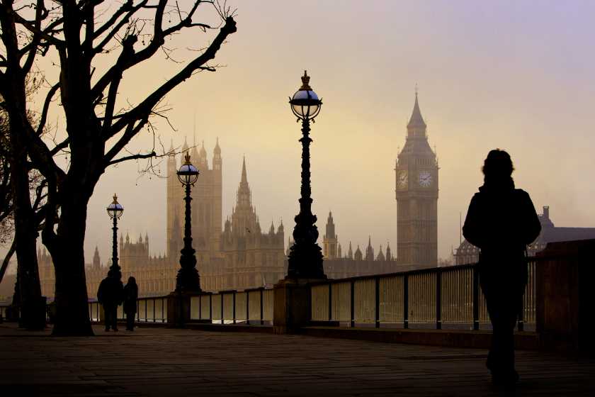Person walking through Big ben and Parliament houses UK during a foggy morning. 