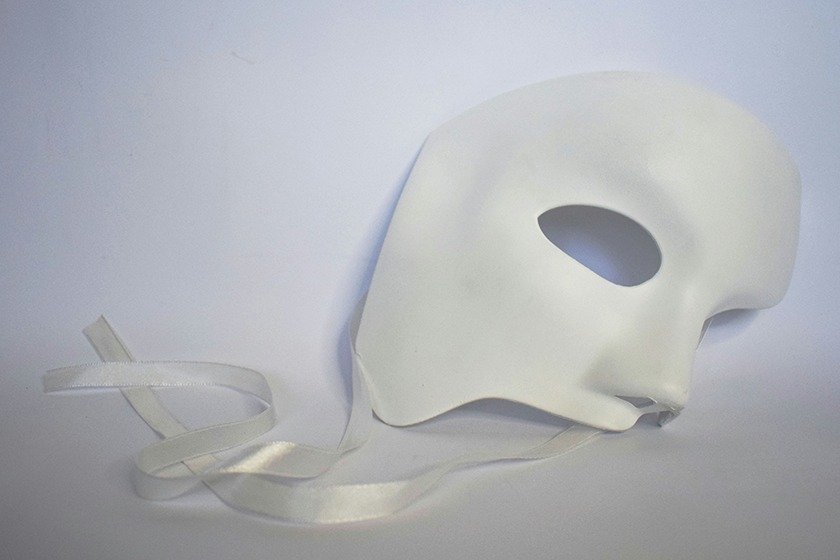 A 'phantom of the opera' mask, on the floor with ribbons trailing