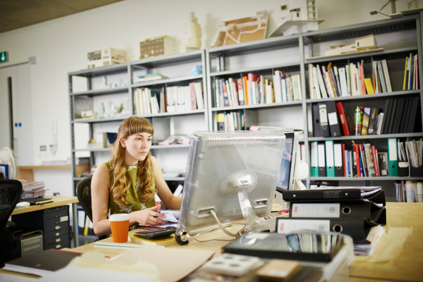 Focused woman working at the office. The vibe of the office attire and space is casual and calming.